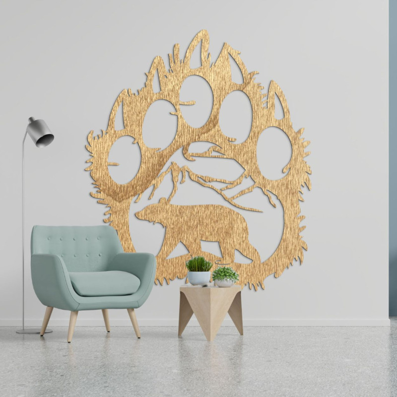 Ein hölzernes Bild eines Bärenfußabdrucks, in das die Silhouette eines Bären geschnitzt ist, der unter den Bergen läuft.