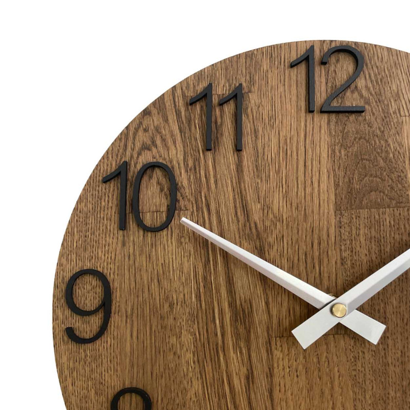 Runde Uhr mit dekorativem Ausschnitt in der Mitte und zartem Holzmuster.